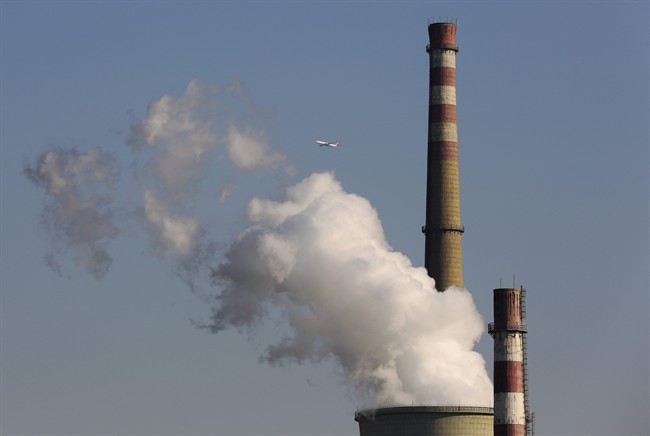 A passenger airliner flies past smokes emitted from a coal-fired power plant in Beijing, China. 