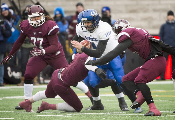 Montreal Carabins quarterback Gabriel Cousineau is tackled by McMaster Marauders' Mike Kashak (77) and Johnathan Ngeleka, right, during first half CIS Vanier Cup football action in Montreal Saturday, November 29, 2014.