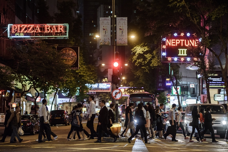 Pedestrians cross a street in front of bars and restaurants in Hong Kong's Wanchai district on November 3, 2014. 