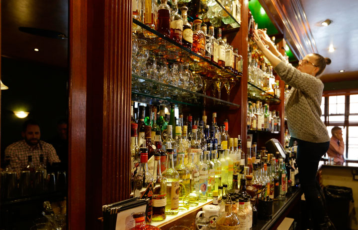 This Oct. 23, 2014 photo shows manager Pamela Montalvo adjusting bottles on a shelf at Daddy-O in New York. Daddy-O has been slinging whiskey since 1999 and offers over 200 bourbons.