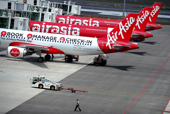 In this Friday, May 9, 2014 file photo, a ground crewman walks by a fleet of AirAsia's passenger jets on the tarmac of the new low cost terminal KLIA2 in Sepang, Malaysia.