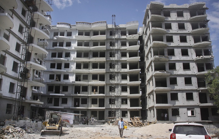 In this photo taken Tuesday, Nov. 4, 2014, a Somali man walks in front of a high-rise apartment building under construction in Mogadishu, Somalia.  