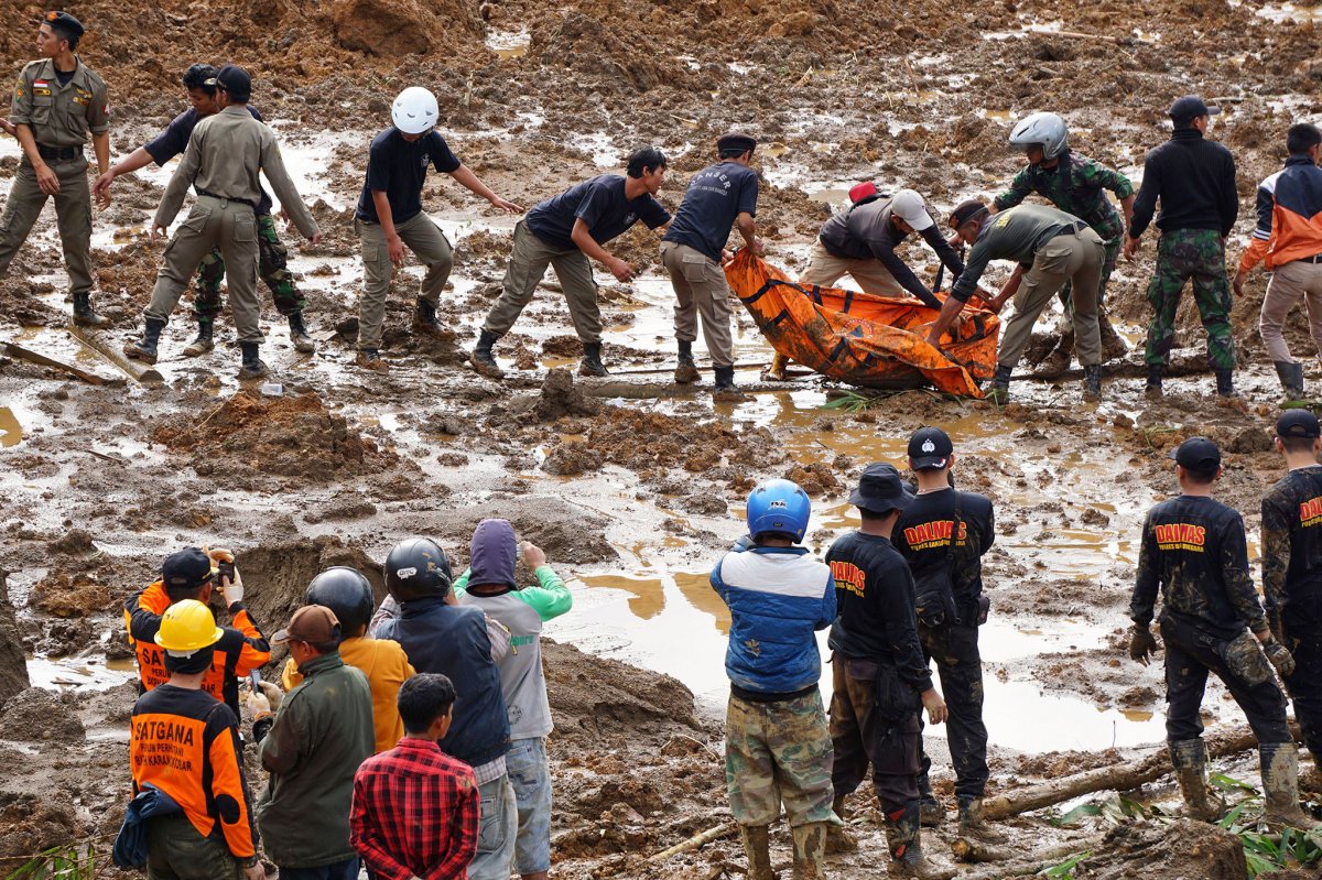Rescuers remove the body of a victim of landslides that swept away houses in Jemblung village, Central Java, Indonesia, Saturday, Dec. 13, 2014. 
