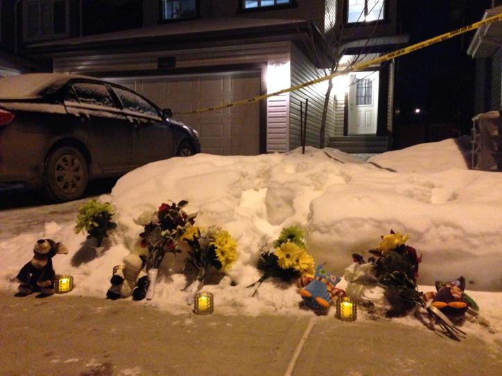 Flowers, candles and stuffed animals are placed in front of the home where seven people – including two children- were found dead.
