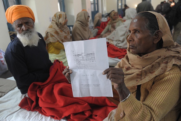 Indian patient Charan Kaur (R), along with her husband Joginder Singh who lost sight in their eyes after undergoing surgery at an eye camp, displays a document from the eye camp as they sit at a government hospital in Amritsar on December 5, 2014. At least 11 people have lost their sight after undergoing free cataract surgery at a camp in northern India, local authorities say, as fears grow the final figure will be far higher.
