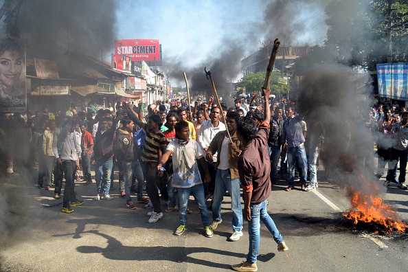 Activists of the Assam Tea Tribes Student Association (ATTSA) shout slogans as they block the road with burning tyres during a protest against attacks on villagers by militants in four different locations, at Biswanath Chariali in the Sonitpur district of northeastern Assam state on December 24, 2014.