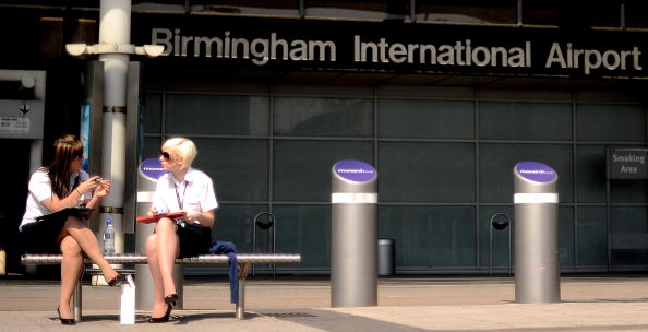 Members of airport staff sit outside a deserted terminal at the Birmingham International Airport in Birmingham, central England, on April 17, 2010. 