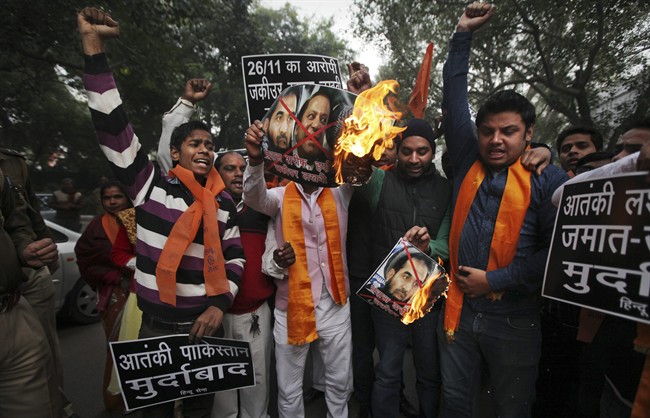 A small group of rightwing activists of the Hindu Sena or the Hindu Army burn posters with portraits of Pakistani Prime Minister Nawaz Sharif, top right, and Zaki-ur-Rahman Lakhvi, the chief suspect in the Mumba attack trial, near the residence of Pakistan High Commissioner to India in New Delhi, India, Friday, Dec. 19, 2014. 