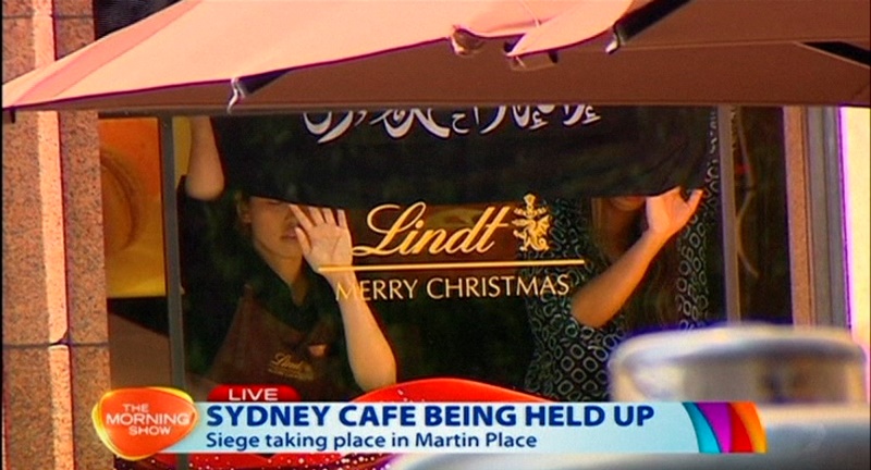 This image taken from video shows people holding up hands inside a cafe in Sydney, Australia Monday, Dec. 15, 2014.