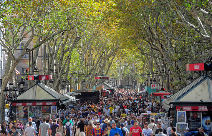 In this Oct. 4, 2010 file photo, people walk along Ramblas Street in Barcelona Spain. The crowded, tree-lined pedestrian mall is filled with street performers, restaurants, bars and kiosks selling souvenirs, flowers and food. It’s an essential Barcelona experience for tourists, and it’s free.