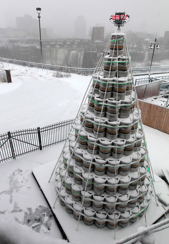 A two-story Christmas tree made of 300 half-barrel beer kegs lights up the sky outside the Genesee Brew House in downtown Rochester, N.Y. on Wednesday, Dec. 10, 2014. The keg tree is trimmed with 600 feet of green lights and topped by a rotating Genesee sign. More than 20 of Genesee's "elves" also known as employees, got to work designing and building the keg tree.