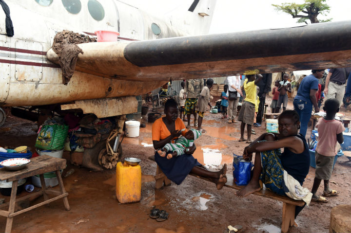 A family rest under the wing of a derelict plane on May 3, 2014 in an IDP camp near Bangui’s Mpoko airport, where the beginning of the rain season has worsensed the situation of people living in the camp.