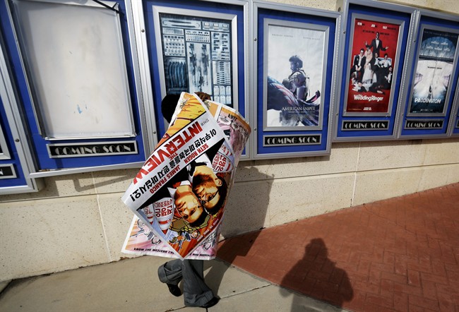 A poster for the movie "The Interview" is carried away by a worker after being pulled from a display case at a Carmike Cinemas movie theater, Wednesday, Dec. 17, 2014, in Atlanta. Georgia-based Carmike Cinemas has decided to cancel its planned showings of "The Interview" in the wake of threats against theatergoers by the Sony hackers.