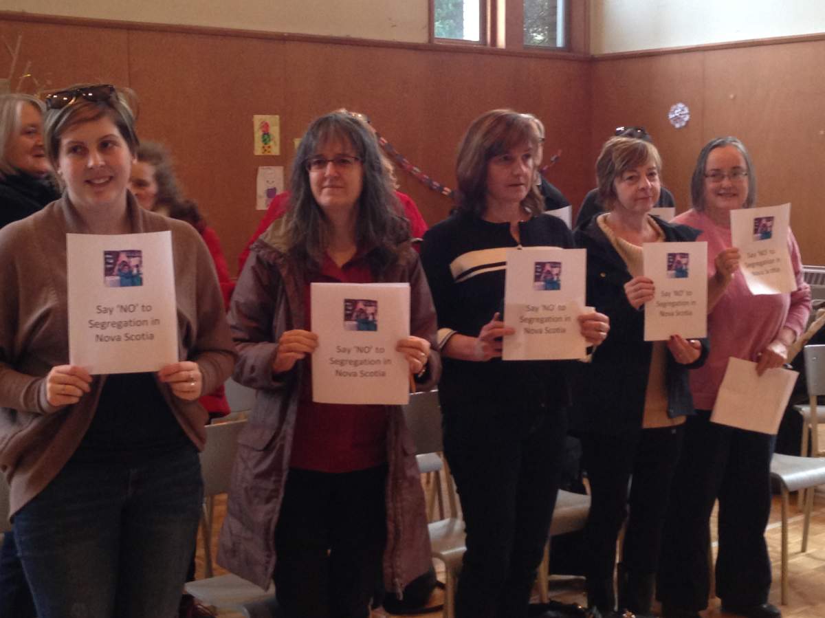 A group of supporters stand holding signs that read "Say 'NO' to Segregation in Nova Scotia".