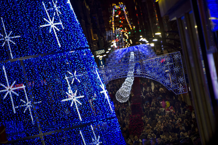 People walk under christmas lights at the Puerta del Sol in Vigo, northwestern Spain, on December 7, 2014.