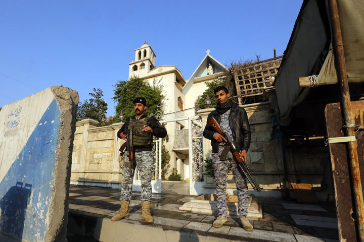 Iraqi security officers stand guard outside of the Virgin Mary Chaldean church in the Karrada neighbourhood of the capital Baghdad on December 21, 2014. 
