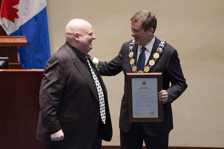 Newly elected Mayor John Tory, right, presents a declaration of office to newly elected councillor and outgoing mayor Rob Ford during an inauguration ceremony in Toronto on Tuesday, December 2, 2014.
