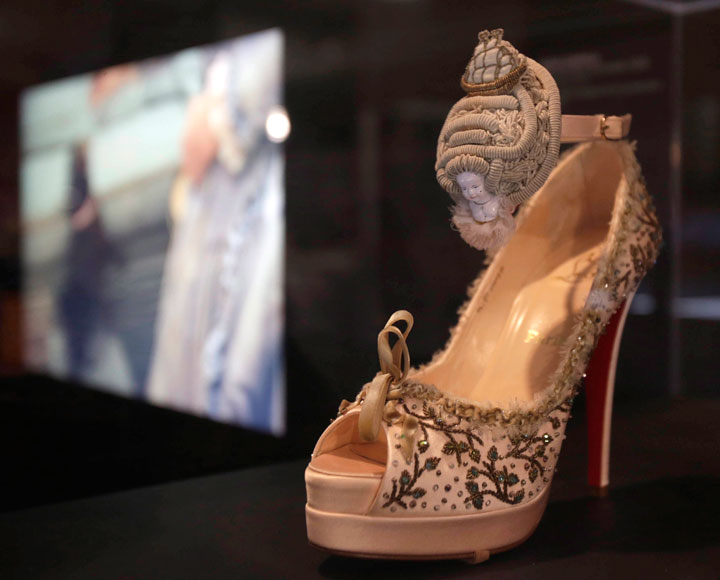 In this Sept. 4, 2014 photo, a 2008 Christian Louboutin shoe embroidered with Marie Antoinette's portrait is on display next to a screening of a scene from the movie "Marie Antoinette" at an exhibit at the Brooklyn Museum in New York. "Killer Heels: The Art of the High-Heeled Shoe" highlights shoes from the 1600s to the present and is open from Sept. 10 through Feb. 15.