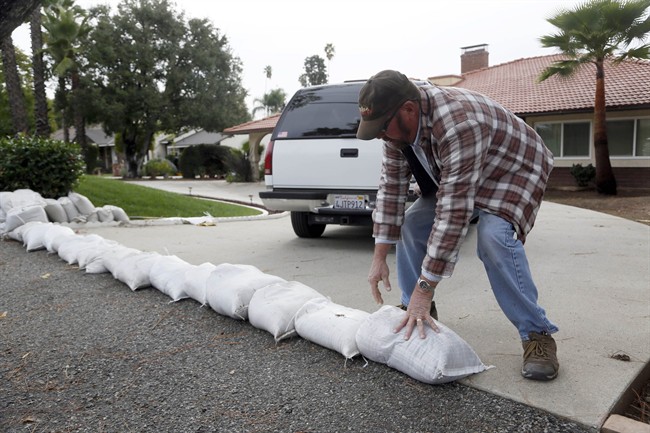 Richard Pope places sand bags along his driveway to protect his home from an expected storm in Glendora, Calif. on Monday, Dec.1, 2014. 