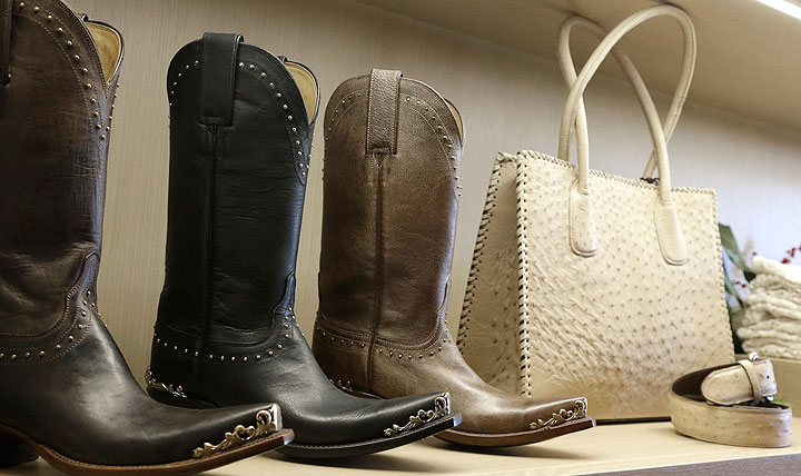 In this Dec. 9, 2014 photo, Western boots share shelf space with a purse and belt at the Lucchese Bootmaker shop in Houston. The Texas-based boot company started making fashion shoes and purses this year in addition to their famous boots.