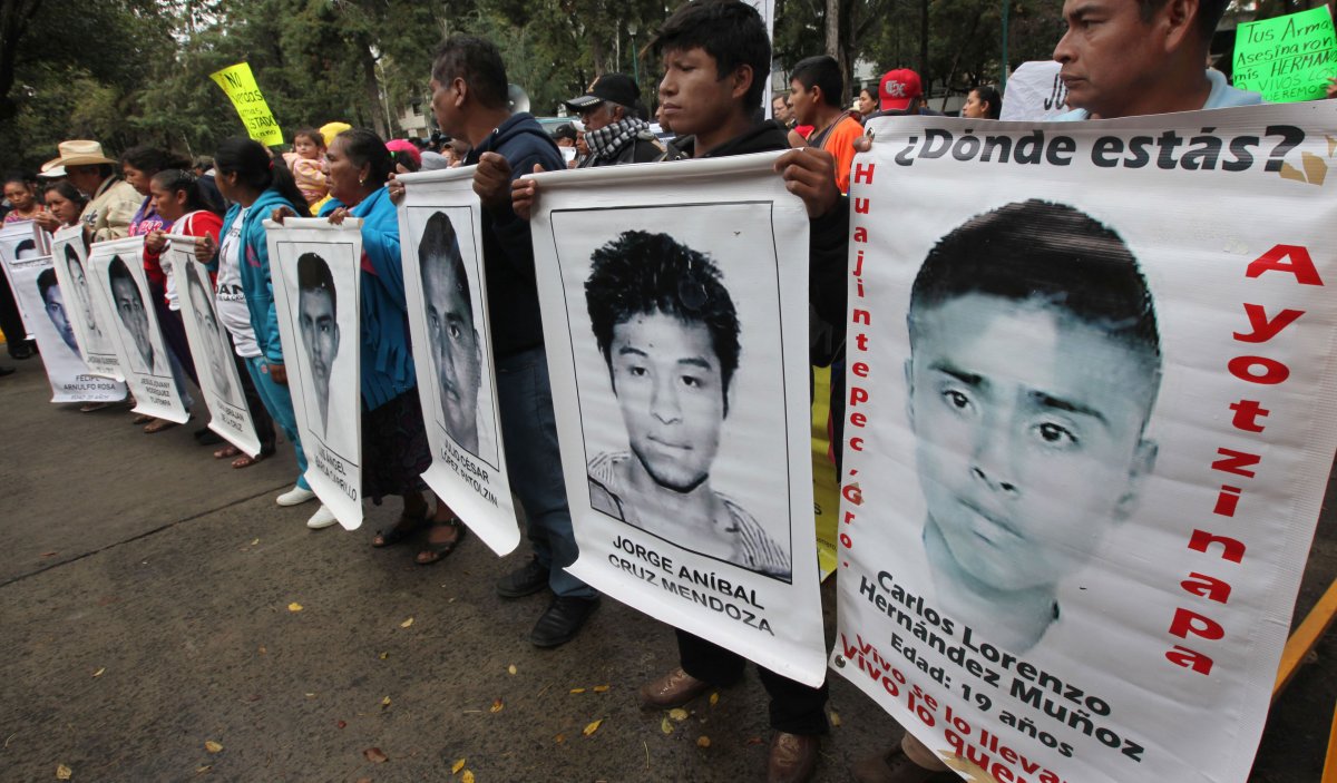 The relatives of 43 missing college students hold posters of their missing loved ones outside Germany's embassy in Mexico City, Dec. 25, 2014. 