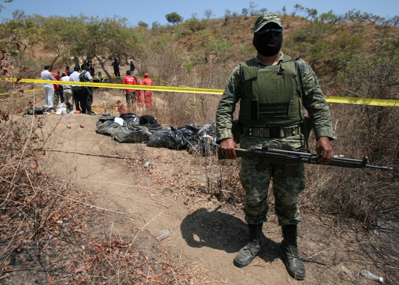 A Mexican soldier stands guard near the place where forensic experts investigate a common grave in Acapulco, Mexico.