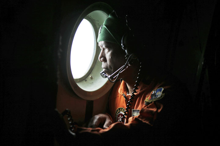 A crew of an Indonesian Air Force C-130 airplane of the 31st Air Squadron looks out of the window during a search operation for the missing AirAsia flight 8501 jetliner over the waters of Karimata Strait in Indonesia, Monday, Dec. 29, 2014. 