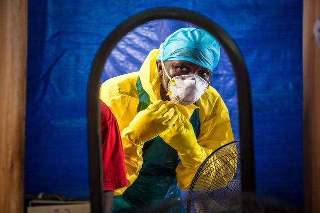 In this Thursday, Oct. 16, 2014 file photo, a healthcare worker dons protective gear before entering an Ebola treatment center in the west of Freetown, Sierra Leone. 