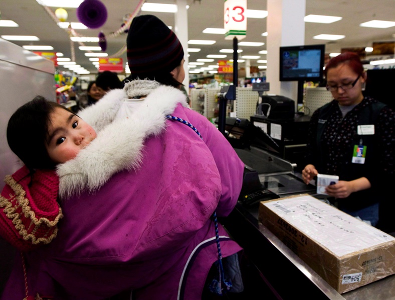 An Inuk child is carried in an amautik by her mother who is paying for groceries in Baker Lake, Nunavut on March 25, 2009. 