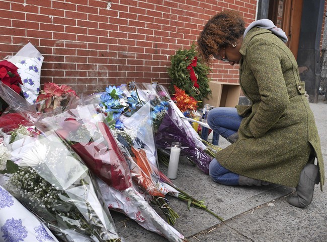 Marea Munro bows her head at an impromptu memorial near the site where two police officers were killed in the Brooklyn borough of New York, Sunday, Dec. 21, 2014. 