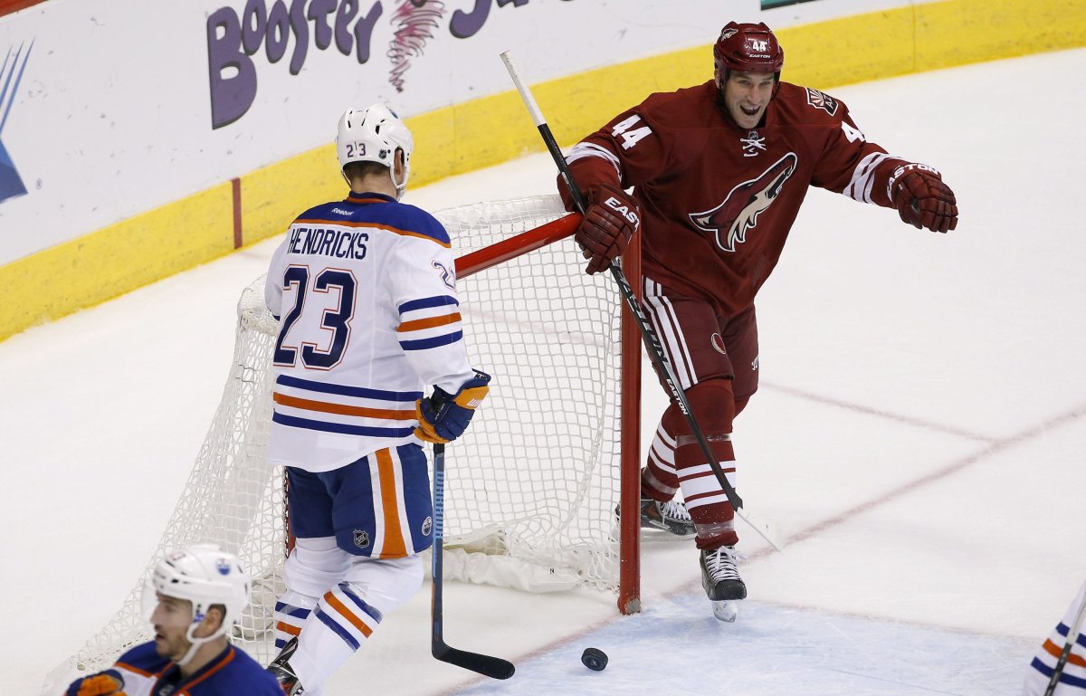 Arizona Coyotes' B.J. Crombeen smiles as he celebrates a goal by teammate Brandon McMillan as Edmonton Oilers' Matt Hendricks looks down at the puck during the second period of an NHL hockey game Tuesday, Dec. 16, 2014, in Glendale, Ariz. 