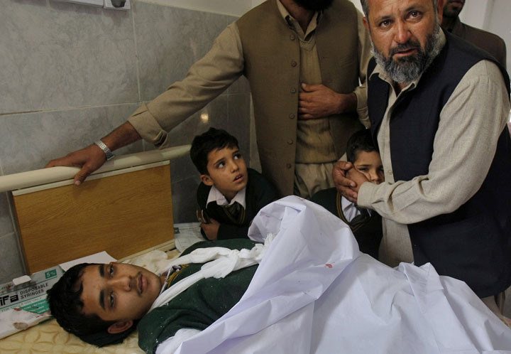 A Pakistani man comforts a student standing at the bedside of a boy who was injured in a Taliban attack on a school in Peshawar, Pakistan, Tuesday, Dec. 16, 2014. 