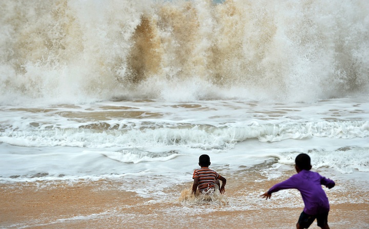 Sri Lankan beachgoers play in the surf in the southern coastal town of Peraliya on December 26, 2014, the tenth anniversary of the deadly Asian tsunami. 