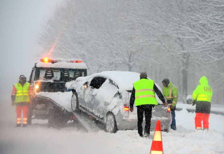 Peopel load a car on a tow truck after a car accident, on December 7, 2012 between Moutiers and Albertville, following heavy snow fall in the area.