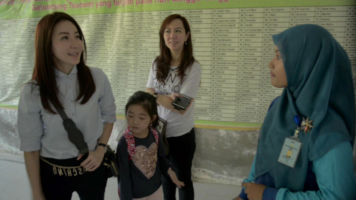 Salmi Hardiyanti guides visitors at the site where a large fishing boat still rests atop the ruins of a home in the fishing village of Lampulo, in Banda Aceh, Indonesia.