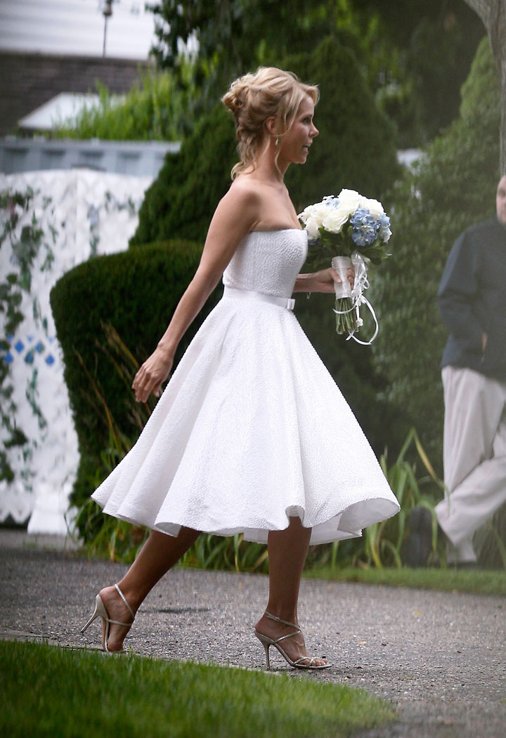 In this Aug. 2, 2014 file photo, actress Cheryl Hines wears a Romona Keveza cocktail length dress as she walks across to the tent at her wedding to Robert F. Kennedy Jr., in Hyannis Port, Mass. The short looks aren't just stand-in dresses originally intended for bridesmaids or cocktail parties. Designers are offering a greater range of shorter styles as more brides break from tradition and personalize their weddings.