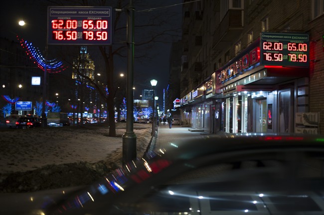 Signs advertising currencies light next to the exchange office in Moscow, Russia, Monday, Dec. 15, 2014. The price of crude oil continued to drop Monday, and Russia's ruble plunged to a record low against the dollar. The ruble crashed through 60 to the dollar, trading at 60.33 by early afternoon. (AP Photo/Pavel Golovkin).