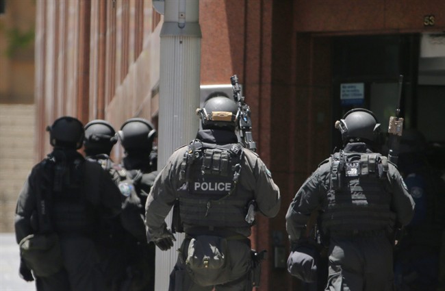 Armed police stand at the ready close to a cafe under siege at Martin Place in Sydney, Australia, Monday, Dec. 15, 2014. 