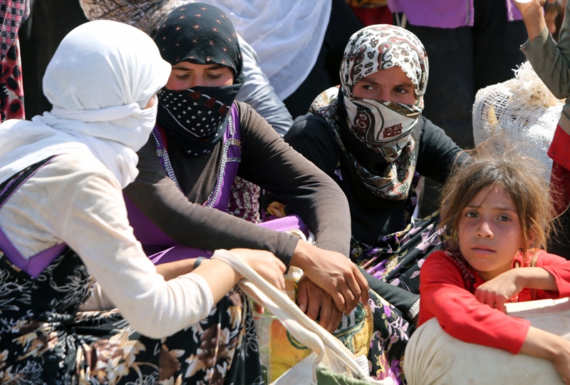 Displaced Iraqi Yazidi women gather sitting at the Bajid Kandala camp near the Tigris River, in Kurdistan's western Dohuk province, where they took refuge after fleeing advances by Islamic State jihadists in Iraq on August 13, 2014. 