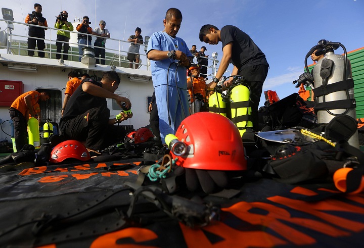 Indonesian navy divers  inspect their equipment on the National Search and Rescue Agency ship prior to a search operation for the victims of AirAsia flight QZ 8501 on the Java Sea, Indonesia, Friday, Jan. 2, 2015.