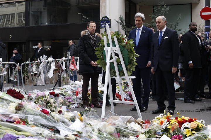US Secretary of State John Kerry (C) and French Foreign Affairs minister Laurent Fabius pay tribute to the victims killed in the attack of the satirical newspaper Charlie Hebdo, on January 16, 2015 at the entrance of the weekly newspaper office in Paris. Twelve people were killed, including cartoonists Charb, Wolinski, Cabu and Tignous and deputy chief editor Bernard Maris when gunmen armed with Kalashnikovs and a rocket-launcher opened fire in the Paris offices of Charlie Hebdo on January 7. 