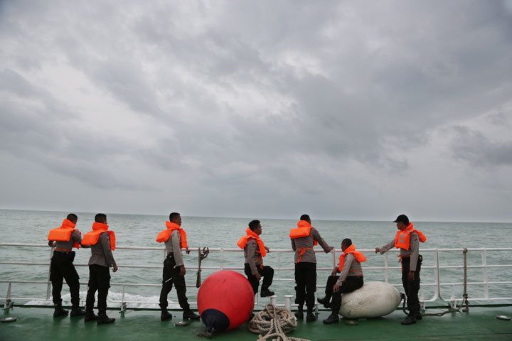 Indonesian police stand on the deck of a National Search And Rescue Agency ship during a search operation for the victims of AirAsia flight QZ 8501 on the Java Sea, Indonesia, Saturday, Jan. 3, 2015. 