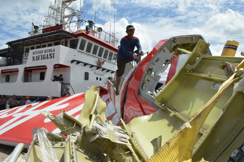An Indonesian worker (top C) cuts the tail of the AirAsia flight QZ8501 in Kumai on January 12, 2015, after debris from the crash was retrieved from the Java sea.