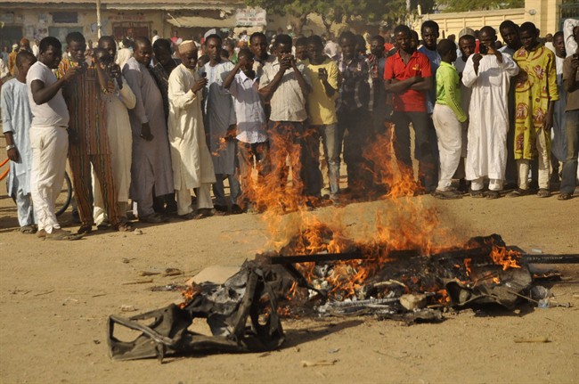 FILE- In this file photo taken on Friday, Nov. 28, 2014, People gather at the site of a bomb explosion in a area know to be targeted by the militant group Boko Haram in Kano, Nigeria.