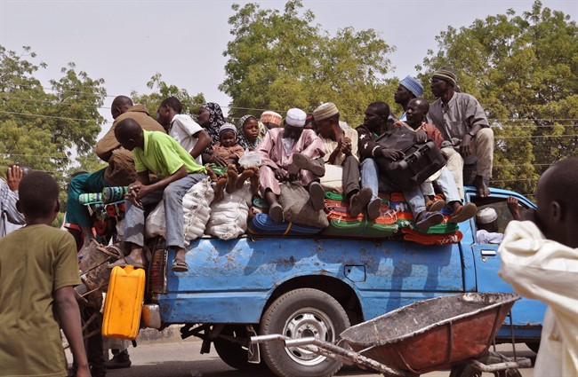 In this photo taken Tuesday, Jan. 27, 2015, villagers sit on the back of a small truck as they and others flee the recent violence near the city of Maiduguri, Nigeria. 