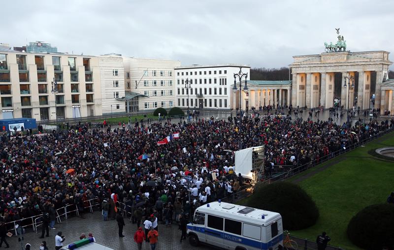 People gather for a vigil, one of several held around the world, to honor the 10 journalists and two police officers murdered when gunmen opened fire at the Parisian offices of the French satirical publication Charlie Hebdo on January 7, 2015, in front of the French embassy on January 11, 2015 in Berlin, Germany.