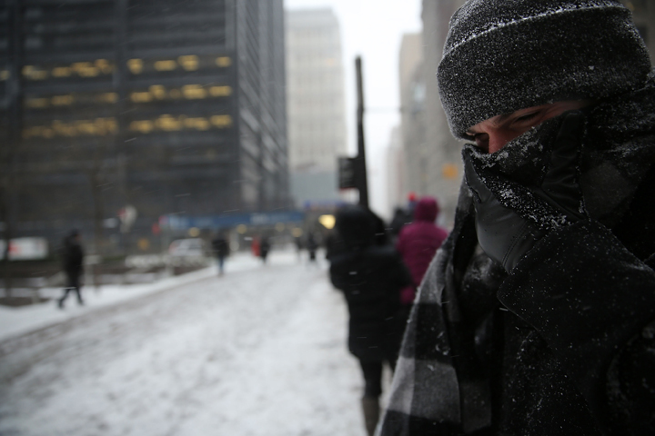 A man who has been waiting over two hours for a city bus covers his face during heavy snow in the financial district of Manhattan on January 26, 2015 in New York City. 
