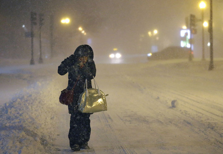 A woman adjusts her hood while walking to work, early Tuesday, Jan. 27, 2015, in Boston. 