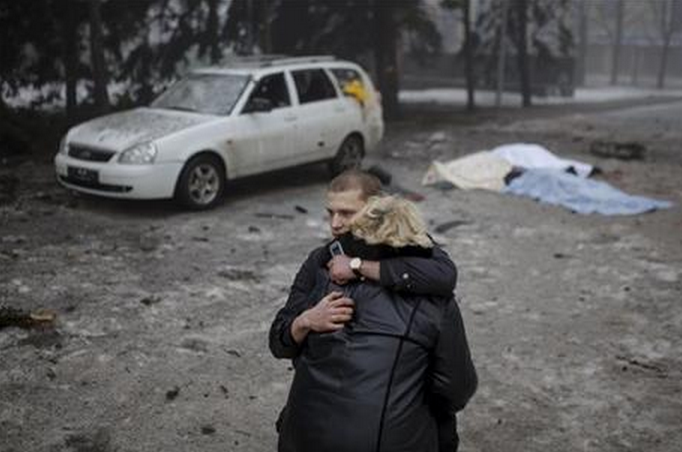 A rebel comforts a wife of a killed civilian in shelling in Donetsk, eastern Ukraine, Friday, Jan. 30, 2015. Artillery fire in the rebel stronghold of Donetsk killed at least 12 civilians on Friday afternoon, the city hall in the rebel stronghold said, as fighting intensifies between pro-Russia separatists and government troops. (AP Photo/Vadim Braydov).
