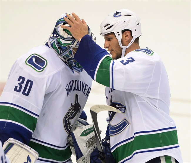 Vancouver Canucks' goalie Ryan Miller (30) is congratulated by Kevin Bieksa (3) after the Canucks' victory 4-1 victory over the St. Louis Blues in an NHL hockey game in St. Louis on Oct. 23, 2014. THE CANADIAN PRESS/AP, Bill Boyce.